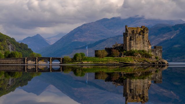 Stunning view of Eilean Donan Castle and bridge reflected on Loch Duich in Scotland.